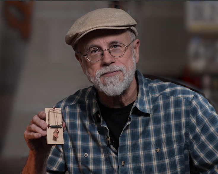 Michael Behe smiling and holding gadget
