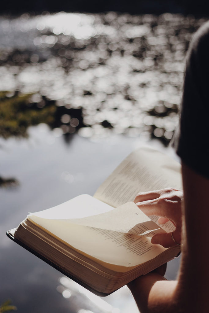 Man reading bible by water